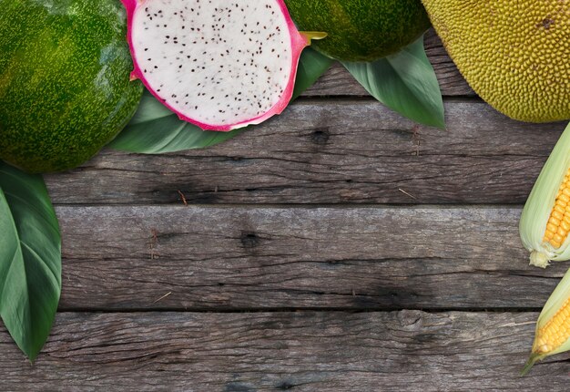 Top views of Wooden desk with fruit, tropical leaves and empty space for background design