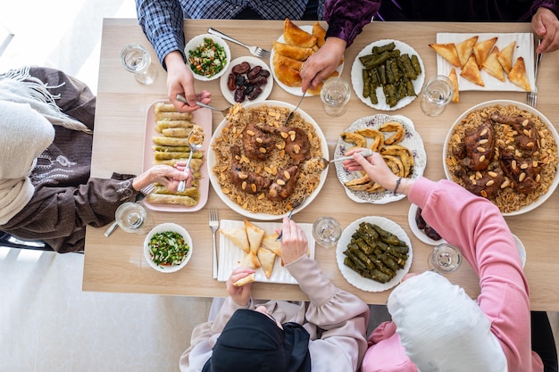 Topbeeld voor een Arabisch gezin dat samen op een houten tafel dinert met vader, moeder, grootvader, grootmoeder en zoon