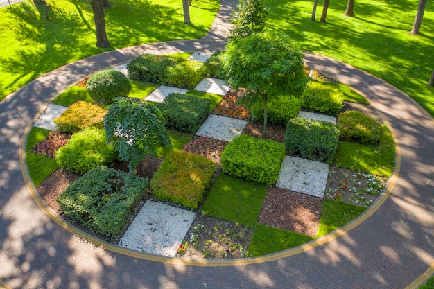 Фото Топиарий для клумбы с деревьями и кустарниками, обрезанными в геометрические формы. заботливо ухаживает садовник. с высоты птичьего полета.