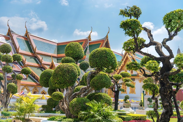 Topiary garden with trimmed trees on green lawn in front of Grand Palace in Bangkok Thailand