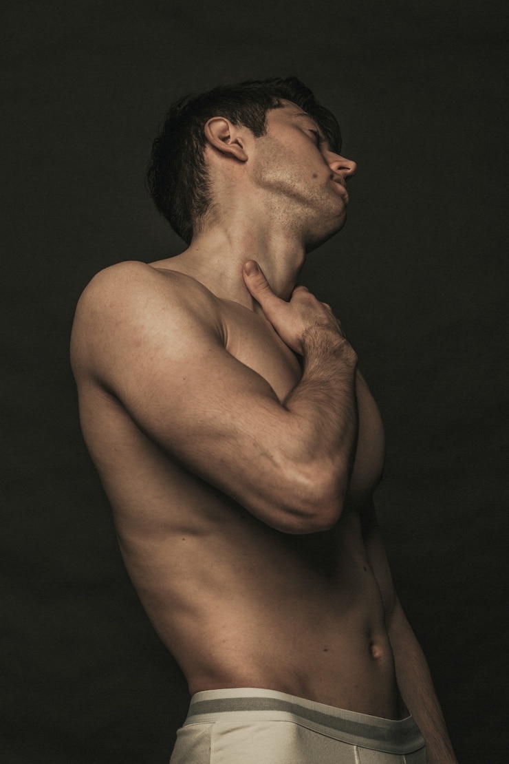 Photo topless handsome guy is touching his neck.