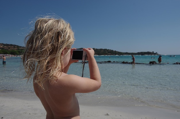 Foto topless meisje fotografeert met camera op het strand