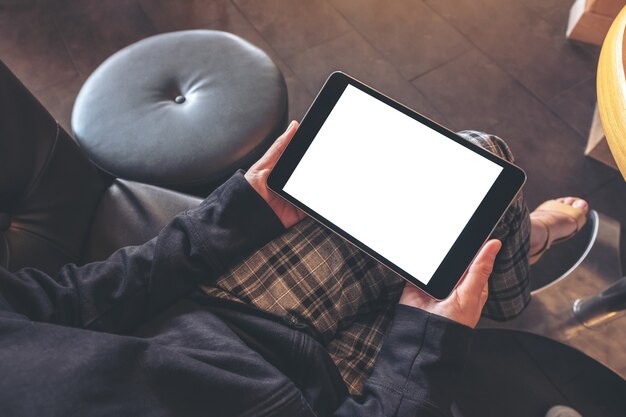 Topview image of a woman holding black tablet pc with blank white screen while sitting in cafe