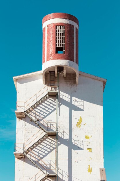 Toren met trappen aan de buitenkant die opstijgen naar een cilindrische toevoeging die in oranje is geverfd