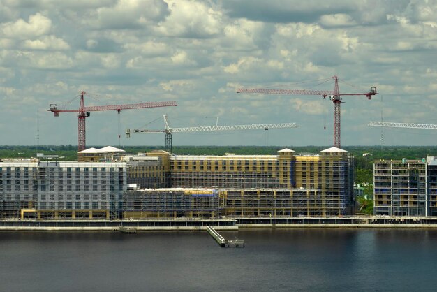 Torenkranen en framestructuur van hoge residentiële appartementsgebouwen op de bouwplaats aan de kust van de zeebaai Vastgoedontwikkeling aan de waterkant