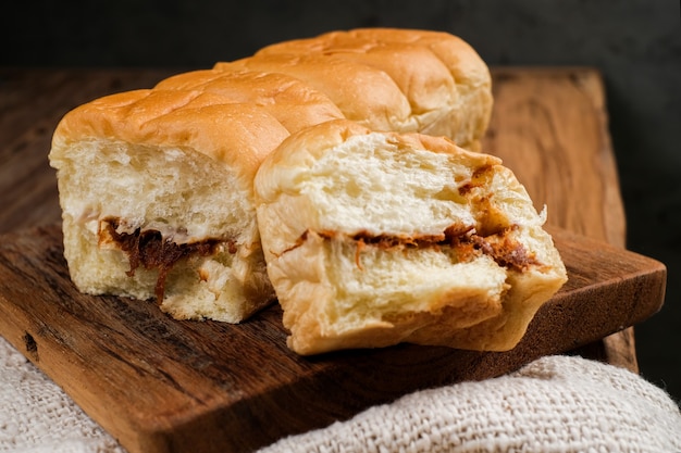 Torn bread filled with beef floss and mayonnaise on a wooden table