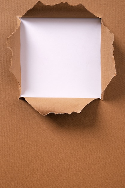 Torn brown paper square hole vertical background frame