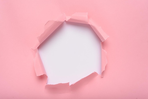 Torn hole in pink paper revealing white background space for text