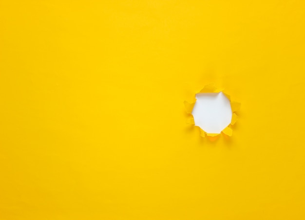 Torn hole in yellow paper. Top view. Minimalistic business concept