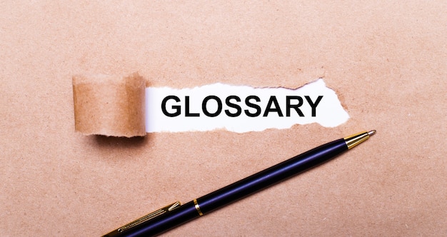 찢어진 크래프트 종이, 흰색 배경에 Glossary라는 텍스트가 있습니다. 근처에 검은색 손잡이가 있습니다. 위에서 보기