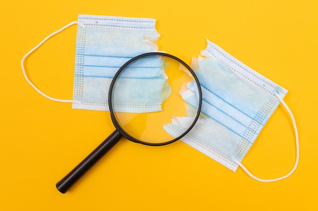 Torn medical face mask lying on yellow table