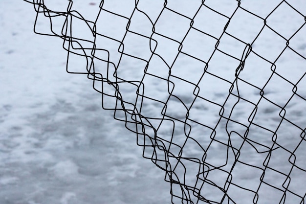 Torn mesh fence on a snow background