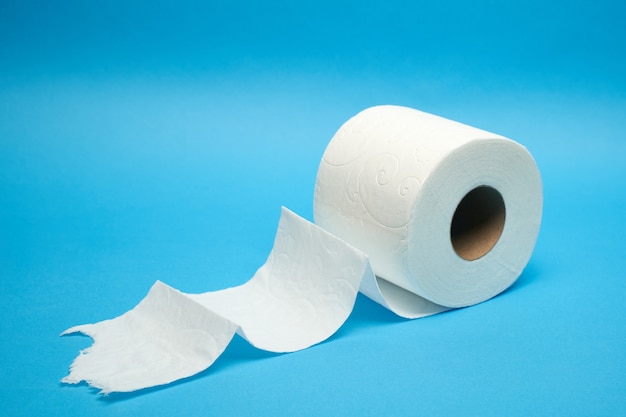 Torn off white toilet paper roll on minimalistic blue background