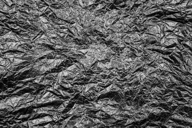 Torn texture of dark black crumpled paper with wrinkles