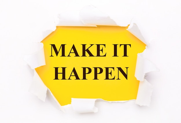 Torn white paper lies on a bright yellow surface with the text MAKE IT HAPPEN