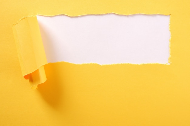 Фото Рваная желтая полоска бумаги на белом фоне разорвана