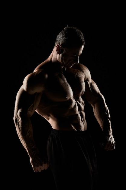 The torso of attractive male body builder on black background.