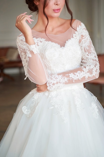 The torso of a bride in a white wedding dress, filmed in a light studio with light from a window.