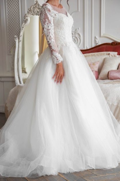 The torso of a bride in a white wedding dress, filmed in a light studio with light from a window.