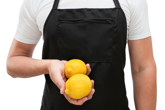 Torso van een man in een zwarte schort met citroenen in zijn hand op een witte achtergrond het concept van koken