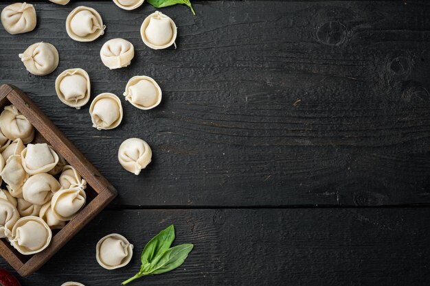 Tortellini with Parmesan and Basil set, on black wooden table table, top view flat lay , with copyspace 