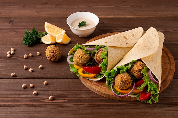 Tortilla's omwikkeld met falafelballen en verse groenten vegetarisch op een houten ondergrond