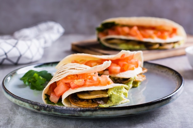 Tortilla with guacamole fried mushrooms tomatoes and herbs on a plate