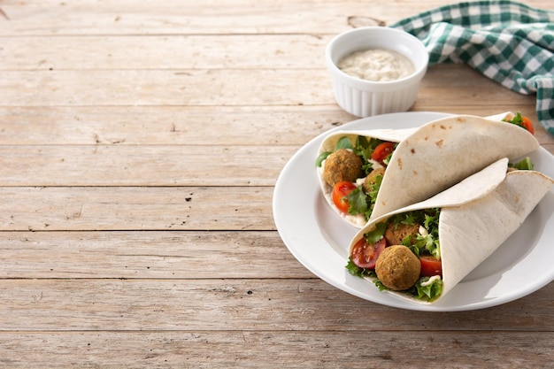 Tortilla wrap with falafel and vegetables on wooden table