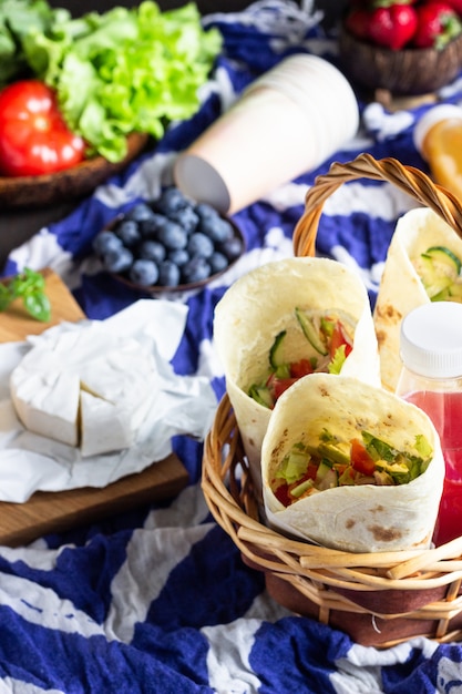 Tortilla wraps met geroosterde kip en groenten, vruchtensappen, groenten en bessen, stokbrood en kaas.