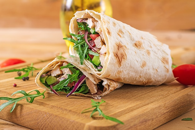 Tortilla wraps met kip en groenten op houten tafel. Kip burrito. Gezond eten.