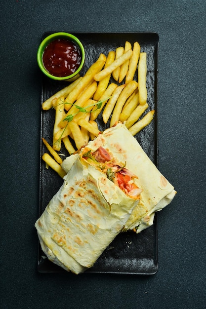 Foto tortilla con verdure e salsiccia e patatine fritte con ketchup su uno sfondo scuro