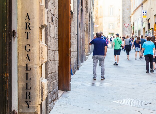 Toscane, Italië. Een kunstgalerie staat aangegeven in een straat vol toerisme.