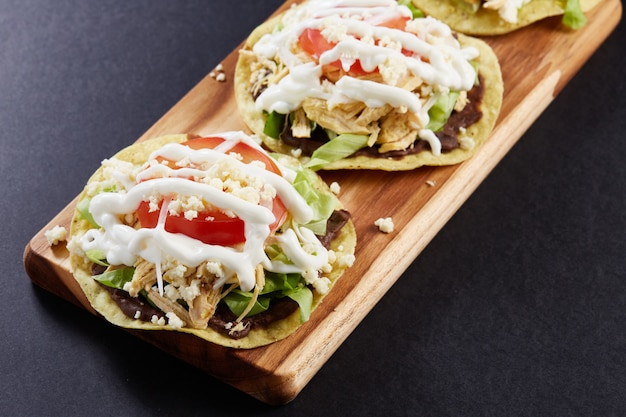 Tostadas de pollo con base de frijoles lechuga tomate queso y crema