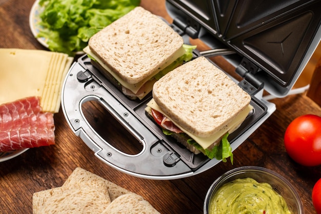 Tosti-ijzer en verschillende ingrediënten op een houten achtergrond Broodjes koken met verschillende vullingen