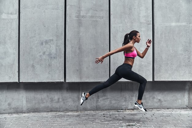 Tot het uiterste gaan. Moderne jonge vrouw in sportkleding die springt tijdens het sporten in de buitenlucht