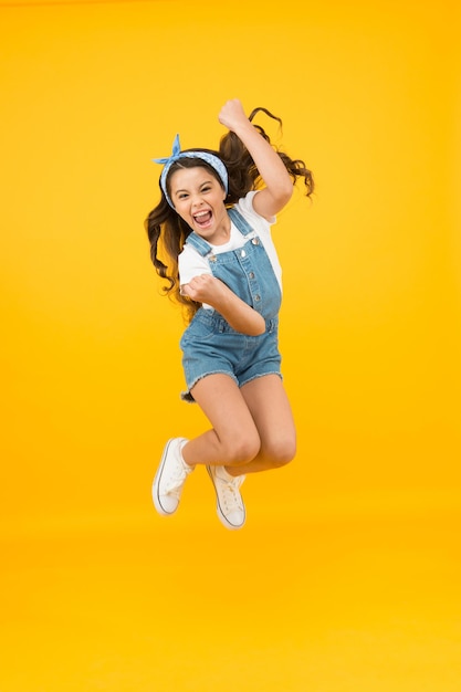 Totally happy. Energy inside. Feeling free. Summer holidays. Jump of happiness. Small girl jump yellow background. Enjoy freedom. Childrens day concept. Spirit of freedom. Active girl feel freedom.