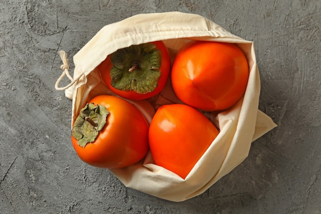 Tote bag with ripe persimmon on gray background