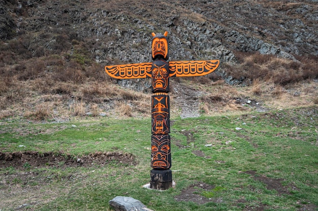 Totem pole with eagle and wings against background of\
nature