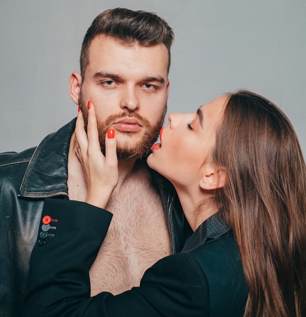 Touch his bristle Girlfriend passionate red lips and man leather jacket She adores male beard Passionate hug Passionate couple in love Man brutal well groomed macho and attractive girl cuddling