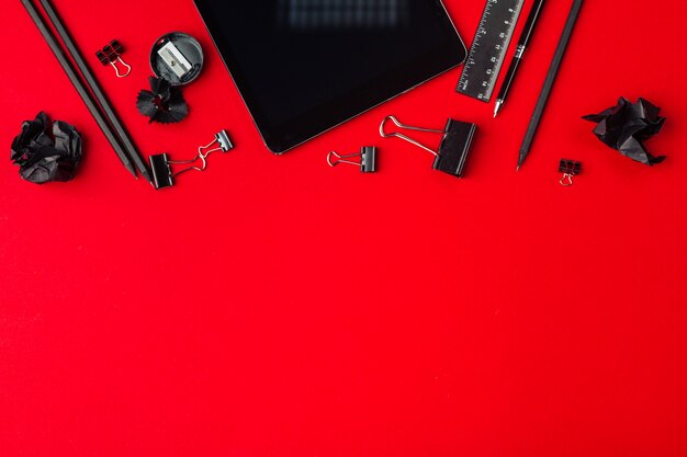 Touch screen device and stationery on red background