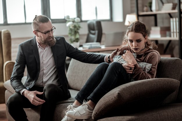 Touching shoulder. Bearded loving father touching shoulder of his daughter feeling very stressed