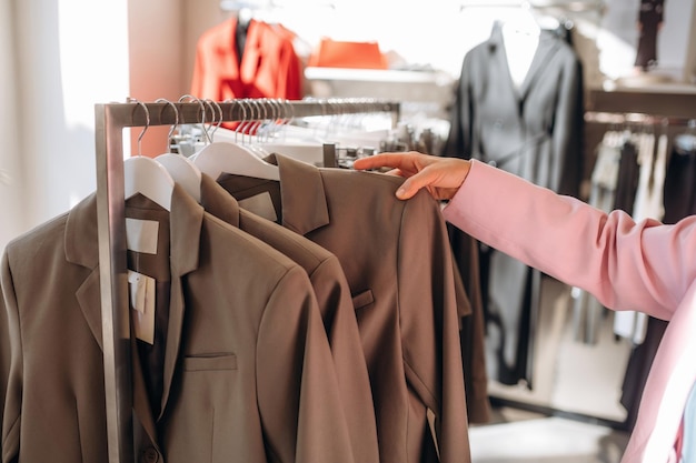 touching the wear close up view of woman that is chooses clothes in the retail shop
