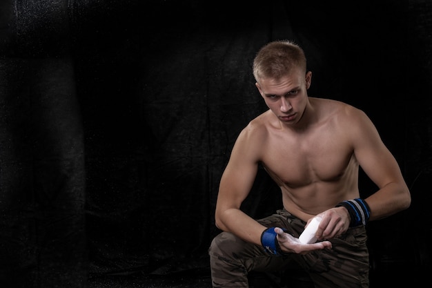 Tough guy with a naked torso rubs his hands with talcum powder