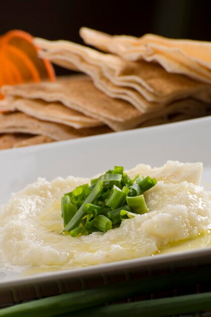 Toum; hommos; labneh; chancliche; garlic paste; arab food; turkish; lebanese; on white plate with orange fabric on background.