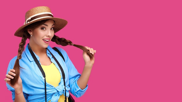 Концепция туризма. возбужденный молодой кавказский турист женщины с фотоаппаратом, изолированным на розовом фоне. битник студентка в повседневной одежде и соломенной шляпе