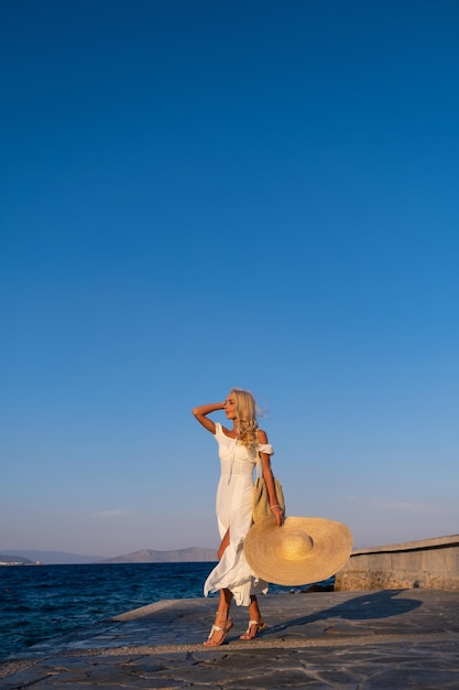 Concetto di turismo giovane donna in viaggio che si gode la vista sul mare in piedi sull'argine della città vecchia