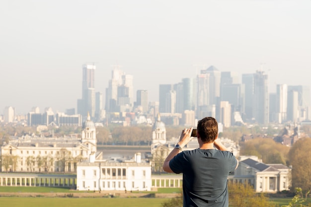 Tourism man taking photo of city view with cell phone while traveling in summer.