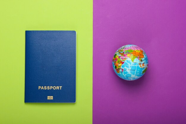 Foto turismo e concetto di viaggio. emigrazione. globo e passaporto sulla parete verde viola vista dall'alto