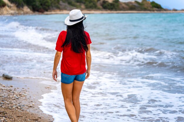 Tourism travel vacation on the rocky sea Girl in red tshirt walking with hair in the wind