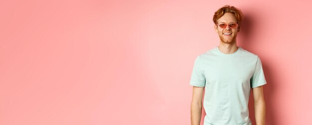 Photo tourism and vacation concept cheerful redhead bearded man in sunglasses and tshirt smiling and looki